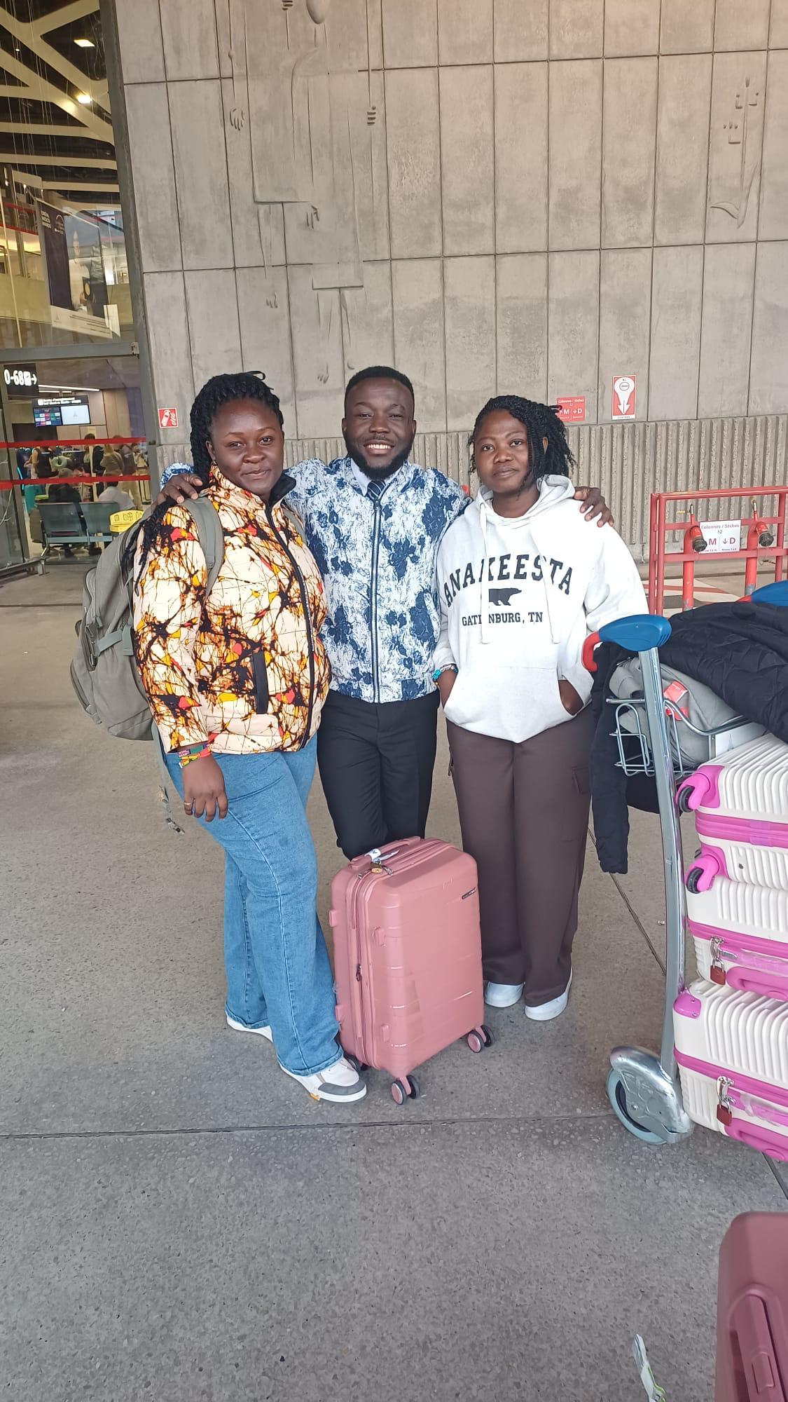 Three travellers met at the airport terminal with their luggage trolley